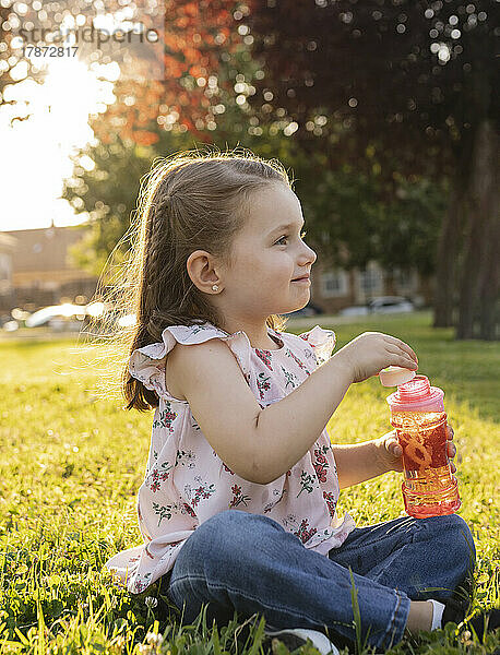 Nettes Mädchen taucht Seifenblasenstab in Flasche im Park