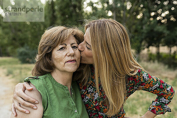 Liebevolle Tochter küsst Mutter im Park