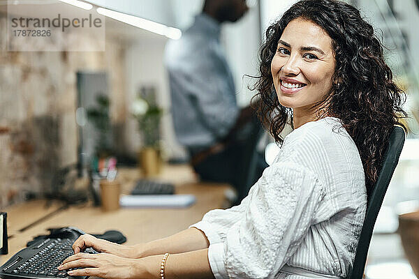 Lächelnde Geschäftsfrau  die im Büro am Computer arbeitet
