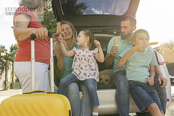 Glückliche Familie  die hinten im Auto Eis isst