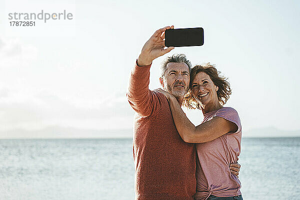 Glückliches Paar macht ein Selfie mit dem Smartphone vor dem Meer