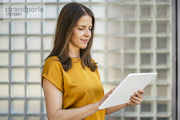 Geschäftsfrau arbeitet an einem Tablet-PC an der Wand im Büro