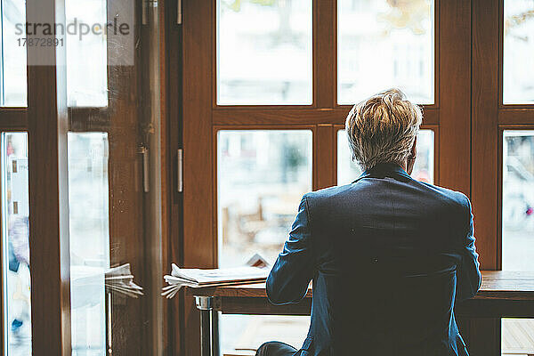 Leitender Geschäftsmann schaut durch Fenster im Café