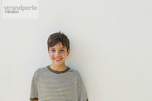 Smiling boy standing in front of white wall