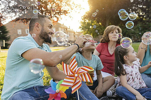Familie bläst gemeinsam Seifenblasen im Park