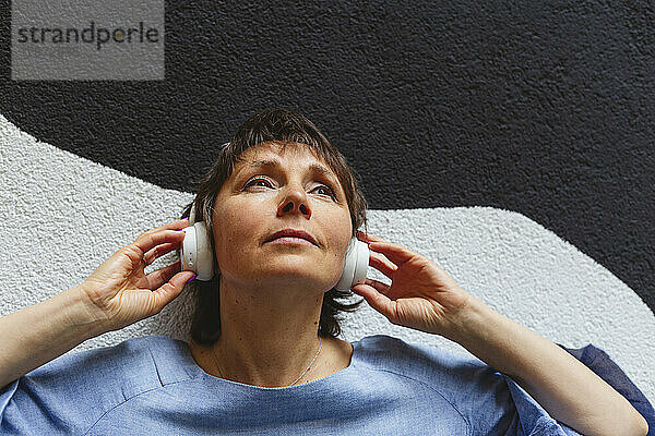Betrachtende Frau  die vor der Wand Musik hört