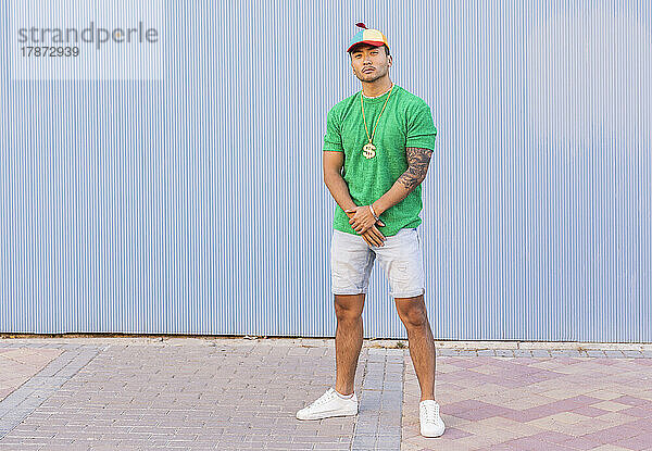 Young man with cap standing in front of wall