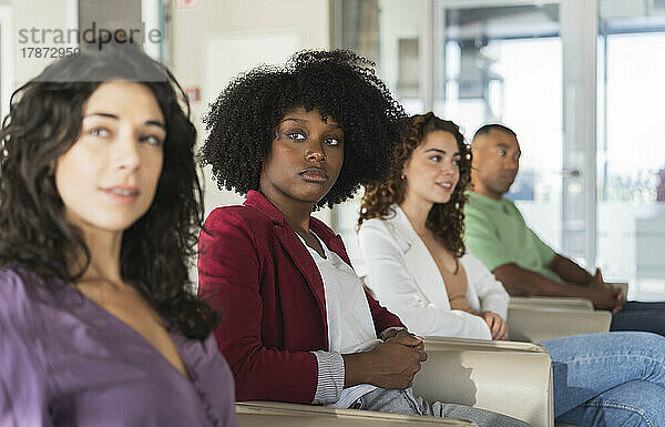 Geschäftsfrau mit Afro-Frisur sitzt neben Kollegen im Büro