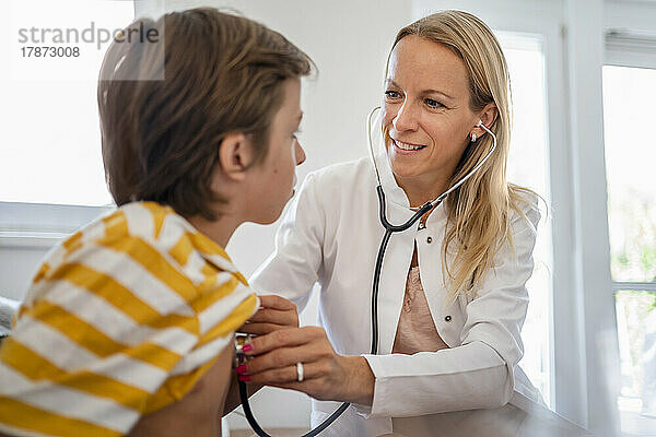 Ärztin mit Stethoskop untersucht Jungen