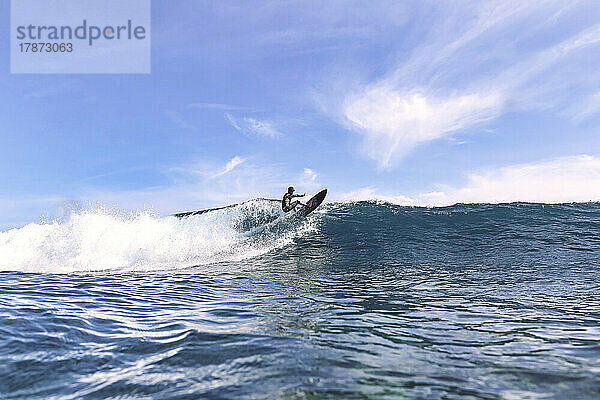 Surfer surft auf einer Welle und planscht im Meer