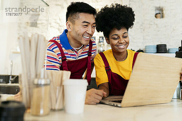 Lächelnder Mann und Frau teilen sich Laptop im Café