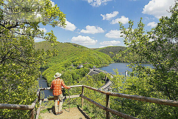 Älterer Mann steht mit Gehstock am Geländer und blickt auf die Urfttalsperre  Nationalpark Eifel  Deutschland