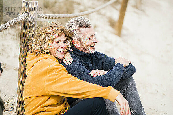 Glückliche reife Frau mit Mann  der am Strand sitzt