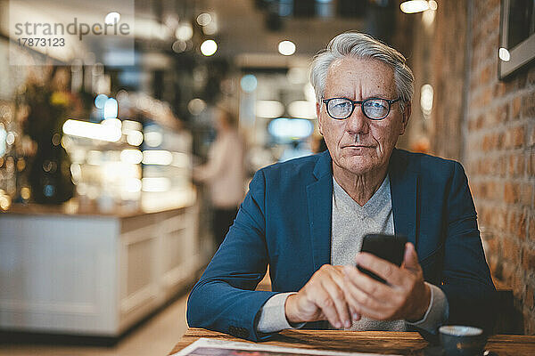 Geschäftsmann mit Mobiltelefon im Café