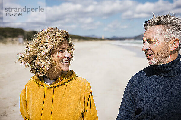 Glückliches älteres Paar  das an einem sonnigen Tag einen Strandspaziergang genießt