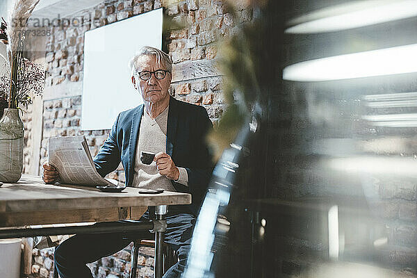 Geschäftsmann mit Zeitung beim Kaffee im Café