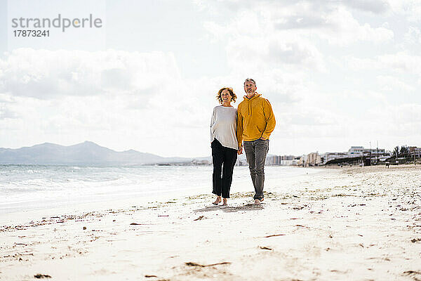 Älteres Paar spaziert am Strand entlang