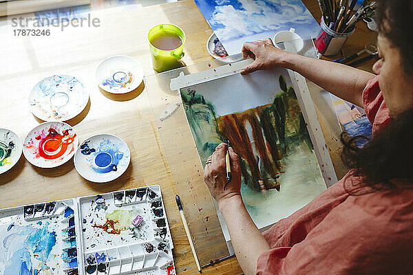 Frau mit Pinsel malt zu Hause Aquarell