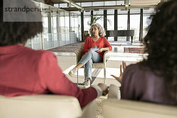 Ältere Geschäftsfrau tauscht Ideen mit Kollegen im Büro aus