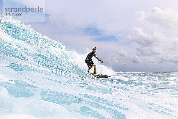 Surfer surft auf dem Meer vor bewölktem Himmel