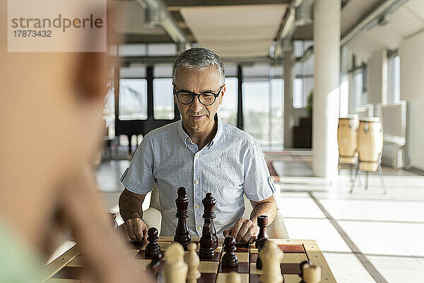 Reifer Geschäftsmann spielt Schach mit Kollegen im Büro