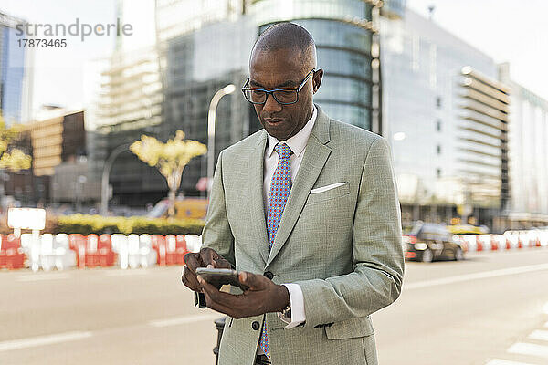 Reifer Geschäftsmann nutzt Smartphone auf der Straße im Finanzviertel