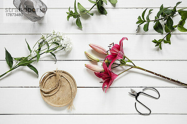 Pair of scissors and freshly cut flowers lying on wooden surface