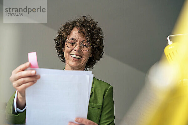 Lächelnde Geschäftsfrau liest Dokument im Büro