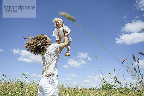 Fröhliche Frau mit Tochter  die sich auf dem Feld vergnügt