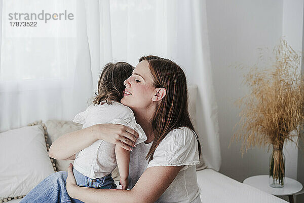 Mutter und Tochter umarmen sich im Wohnzimmer