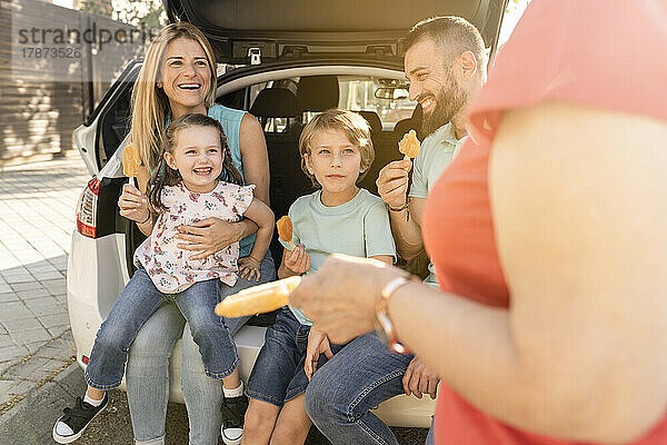 Glückliche Familie mit Eiswürfeln  die hinten im Auto sitzen