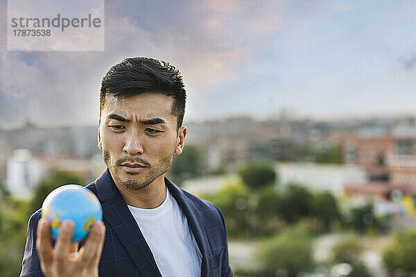 Young businessman staring at globe