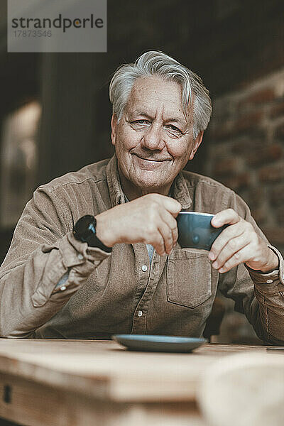 Lächelnder älterer Mann beim Kaffee im Café
