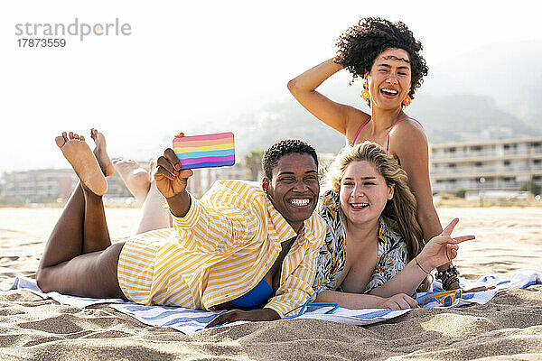 Glückliche gemischtrassige Freunde  die am Strand ein Selfie mit dem Handy machen