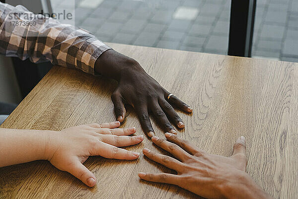 Hands of multiracial friends on table at cafe