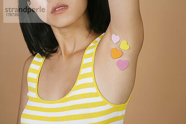 Woman with heart shape stickers on armpit