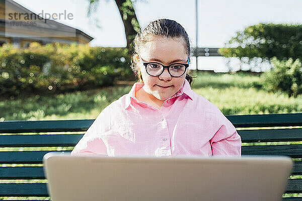 Teenager-Mädchen mit Down-Syndrom benutzt Laptop im Park