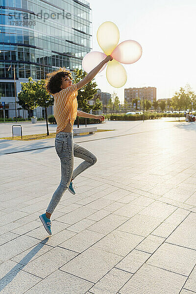 Glückliche Frau  die am Fußweg mit Luftballons spielt