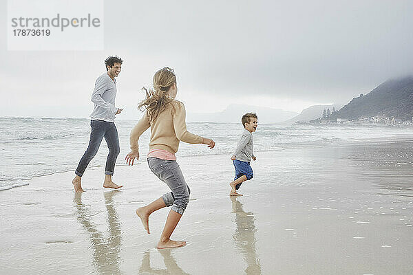 Vater läuft mit Sohn und Tochter am Strand