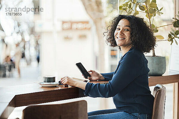 Glückliche Frau mit Handy im Café