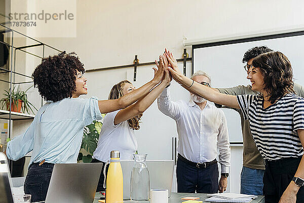 Fröhliche Geschäftskollegen geben sich im Büro gegenseitig High-Five