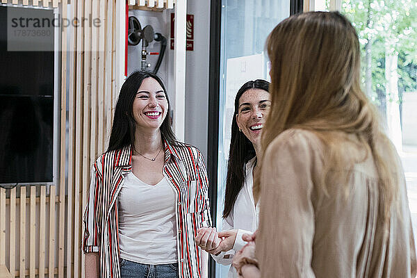 Drei glückliche Geschäftsfrauen unterhalten sich im Büro