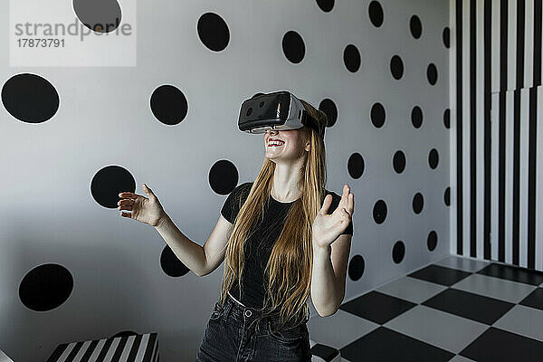 Glückliches Mädchen  das es genießt  ein Virtual-Reality-Headset an einer gepunkteten Wand zu tragen