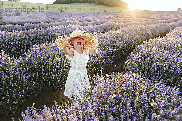 Sad girl wearing hat shouting amidst lavender plants