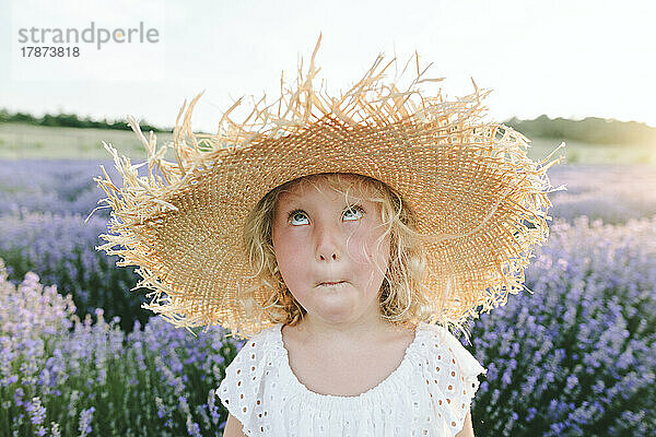 Mädchen mit Hut macht Gesicht im Lavendelfeld