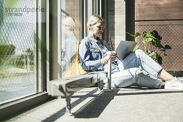 Geschäftsfrau sitzt mit Tablet-PC am Modell einer Windkraftanlage im Büro