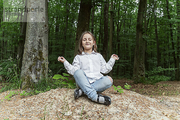 Glückliches Mädchen mit geschlossenen Augen meditiert im Wald