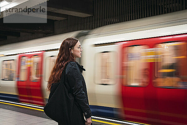 Junge Frau steht vor der U-Bahn am Bahnsteig