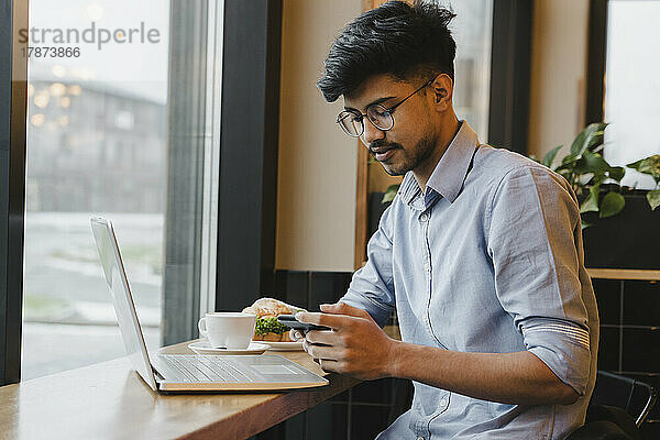 Freiberufler nutzt Smartphone am Tisch im Café