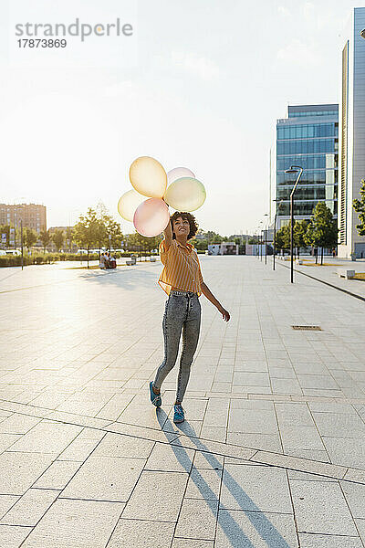 Junge Frau genießt es mit Luftballons am Fußweg